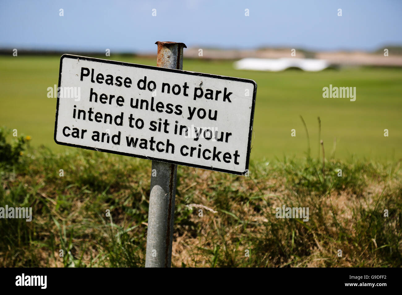 A warning sign outside a cricket pitch by the coast Stock Photo