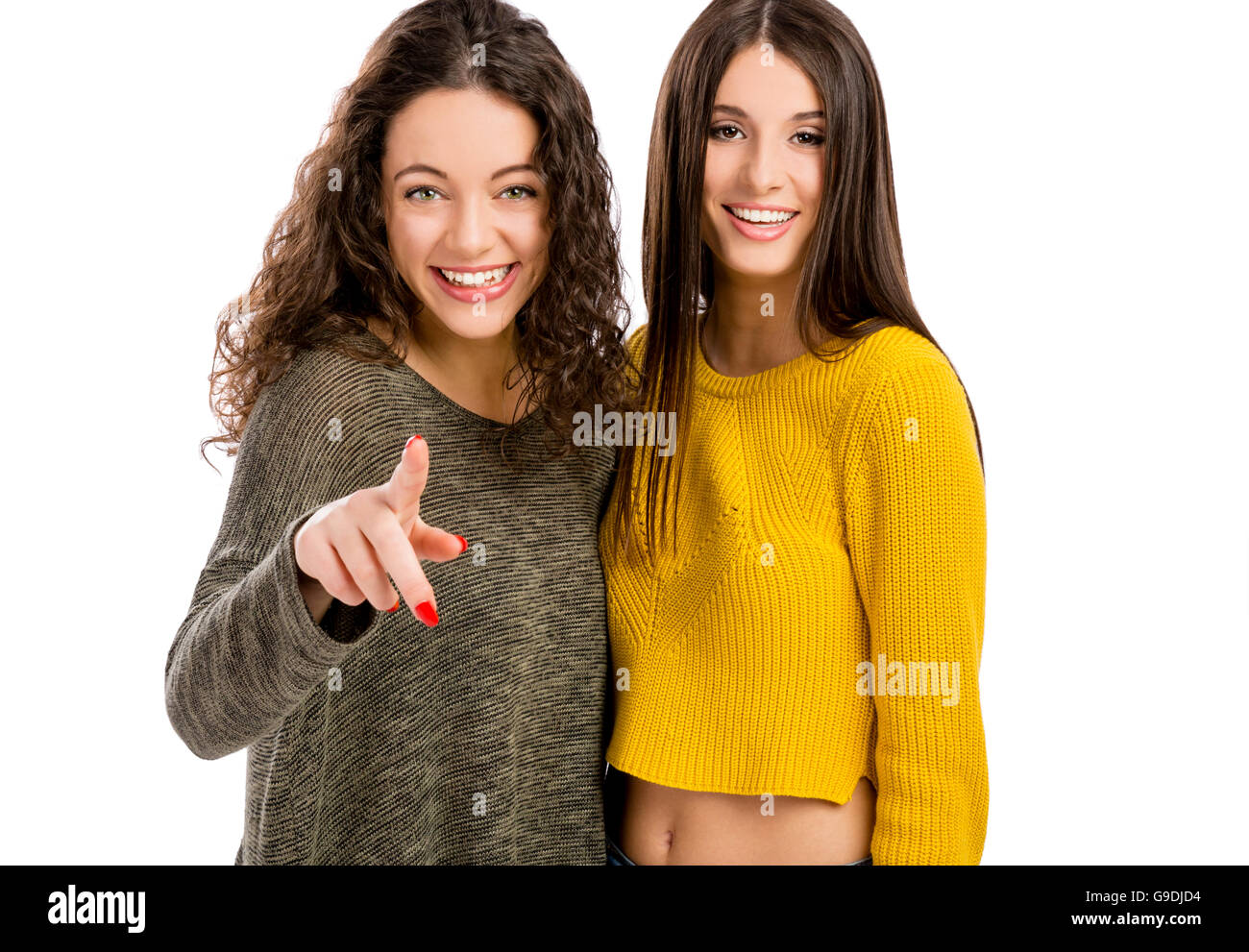 Studio portrait of two beautiful girls pointing and looking to the camera Stock Photo