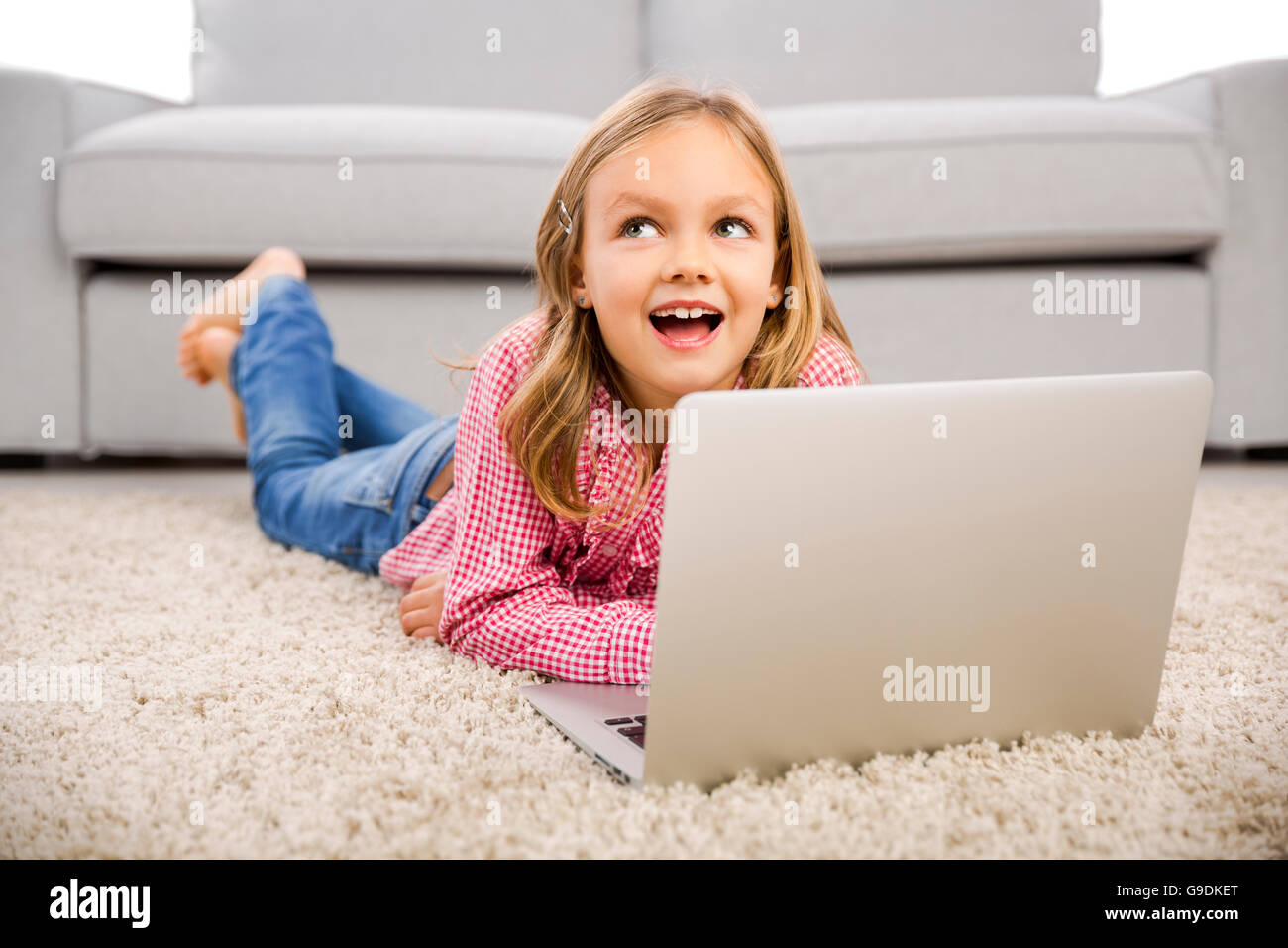 Happy little girl at home working with a laptop Stock Photo - Alamy