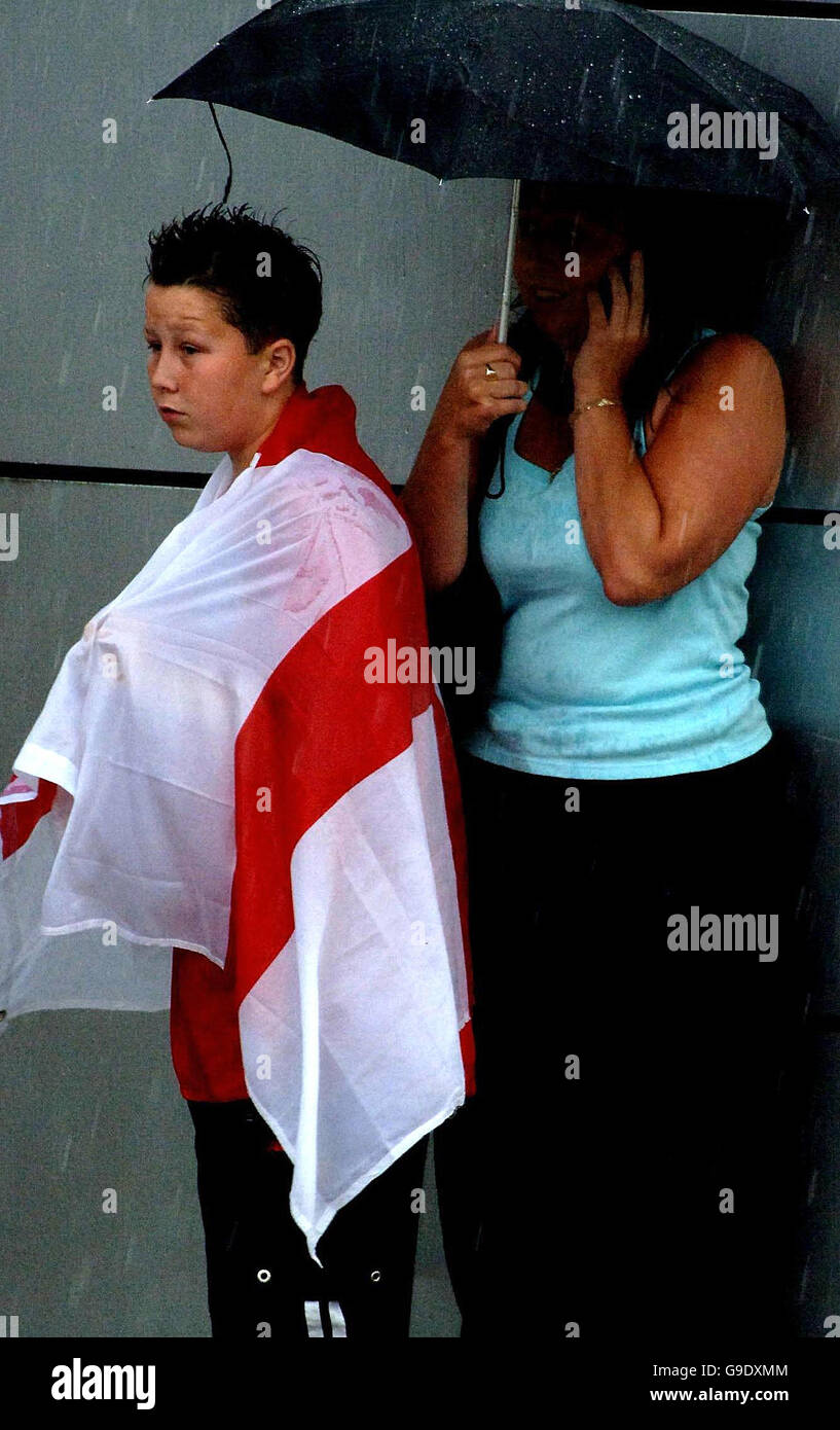 Left waiting in torrential rain, a young England supporter waits in vain at Manchester Airport where the England football team were expected to arrive before bad weather diverted their flight to Liverpool. Stock Photo