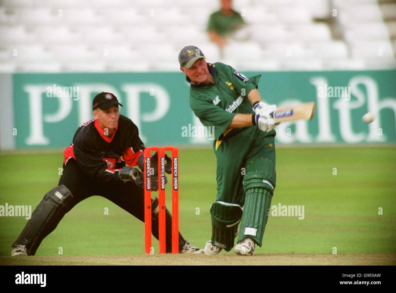 Nottinghamshire Outlaws' Paul Johnson (r) hits a boundary, watched by Glamorgan Dragons' Mark Wallace (l) Stock Photo