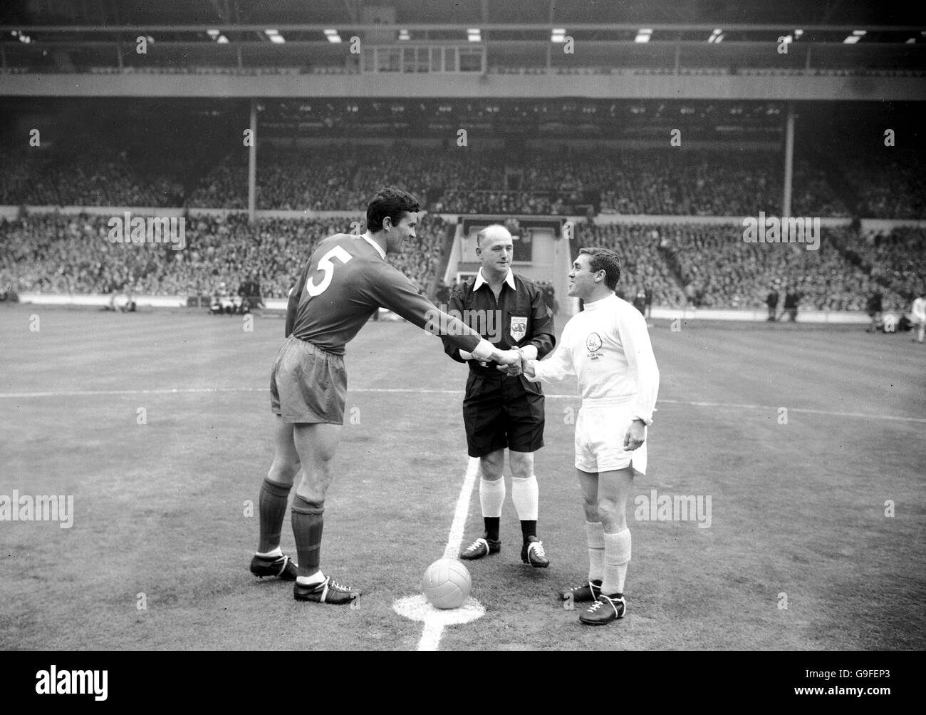 Leeds United captain Bobby Collins (r) shakes hands with Liverpool captain Ron Yeats (l), watched by referee W Clements (c) Stock Photo