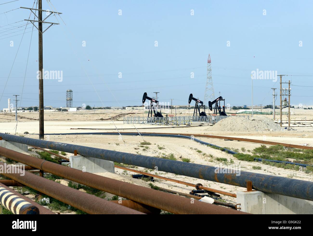 Pumpjacks aka oil horse, nodding donkey, oil jack, beam pump raising crude oil in Bahrain desert at Sakhir on the Persian Gulf Stock Photo