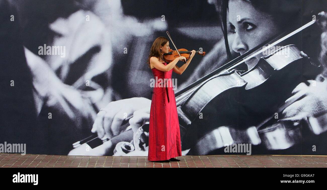 Maxine Moore, violist with the London Symphony Orchestra, plays in front of a large-scale photograph of herself at The Barbican Centre, in central London. Stock Photo
