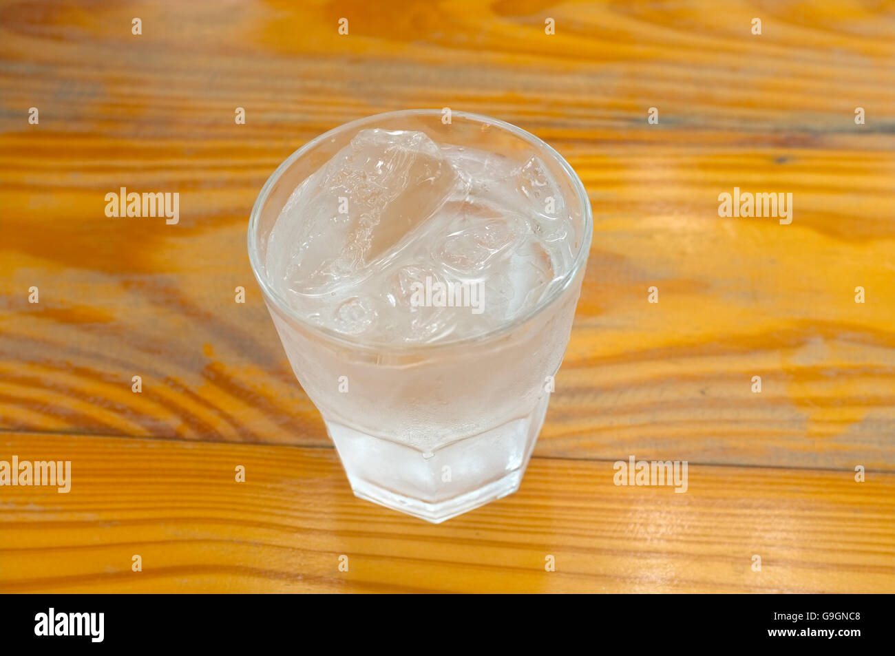 Glass of pure water and ice cube on wooden background Stock Photo
