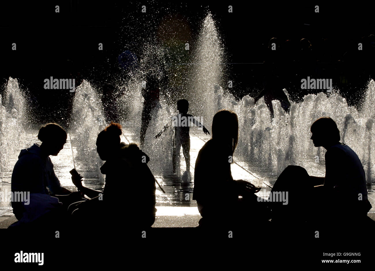 Children play in the water feature in the recently renovated Piccadilly Gardens in Manchester. This year saw the tenth anniversary of the Manchester IRA bombing, since then the city centre has been transformed. Stock Photo