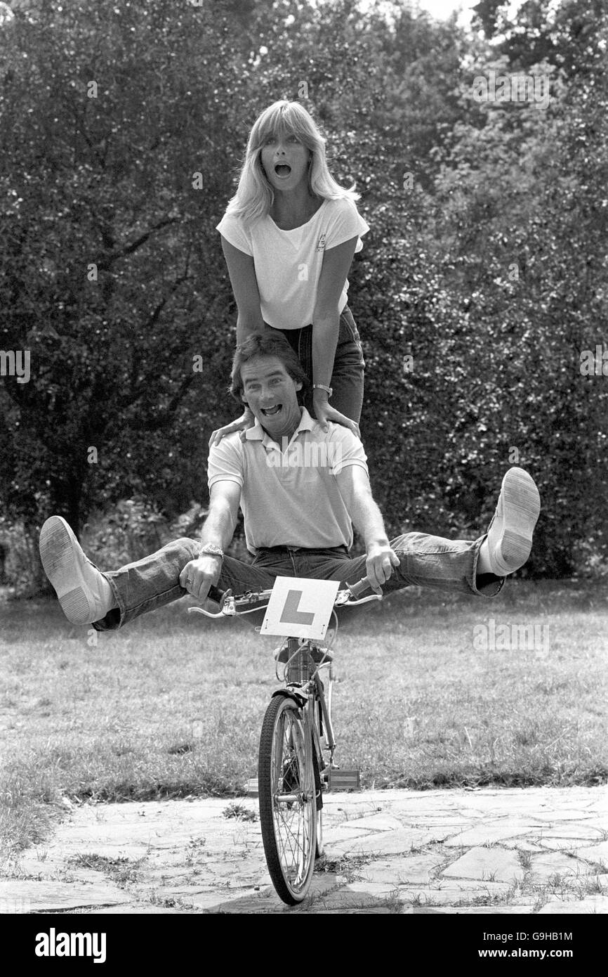 Motorcycling. Motorcyclist Barry Sheene fools around on a bicycle with his girlfriend Stephanie McLean Stock Photo