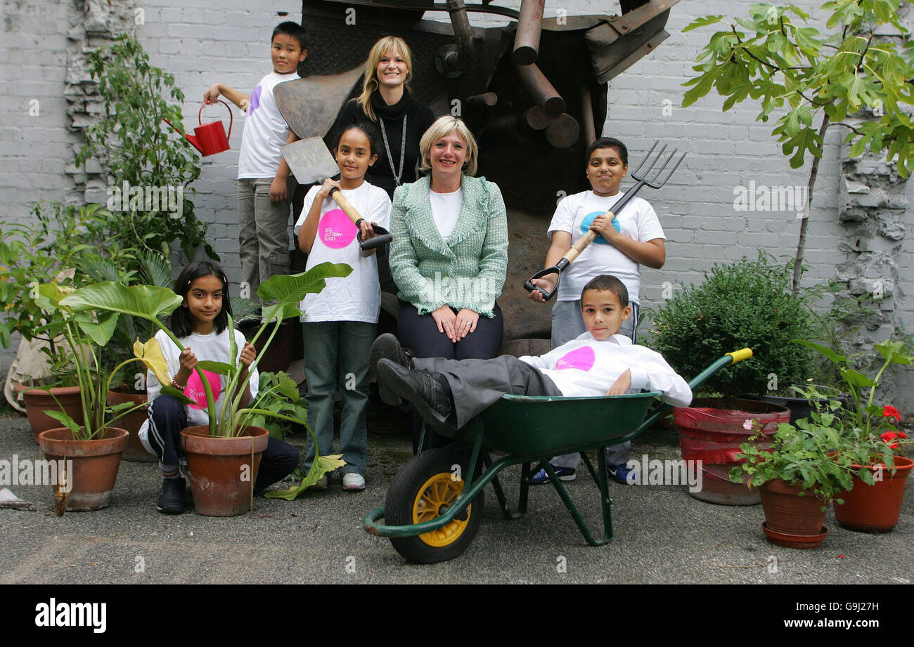 Children from the Clara Grant Primary School (Left-Right: Saba Qureshi (age 9),Ngoc Pham at top with watering can (age 9),Halima Khanam (age 10),Annie Bicknell,head of Education Bow Arts Trust,Helen Thorne,Head of Policy at the Big Lottery Fund,Azim Ahmed (age 10) and Jaydon Sullivan in barrow (age 8) in east London, which is teaming up with the Bow Arts Trust to turn the space the children are standing in from a car park into a `breathing place` in the heart of London`s East End. Stock Photo