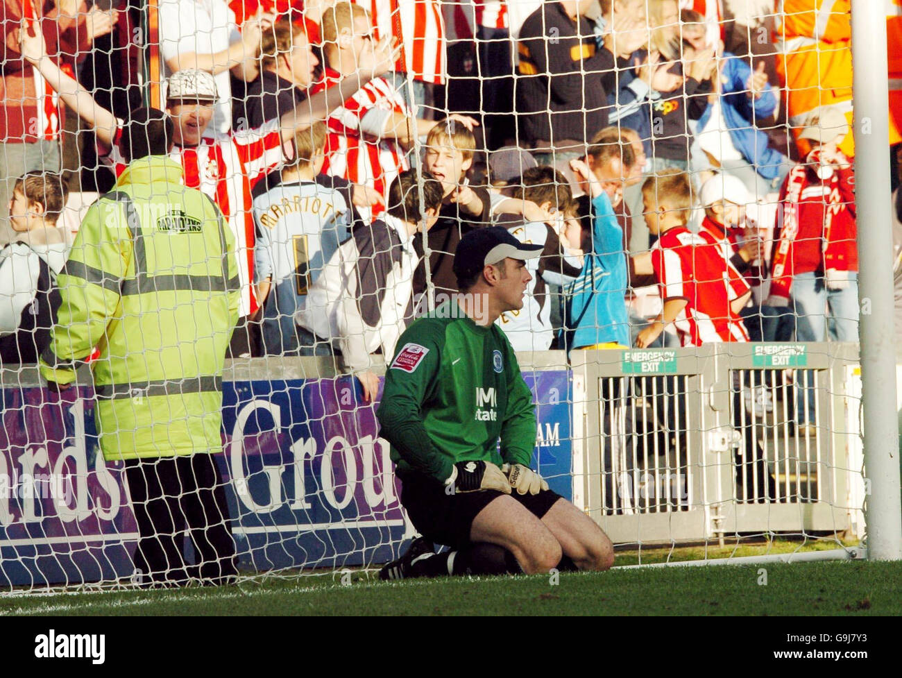 Rochdale's goalkeeper Matthew Gilks kneels in his goalmouth as Lincoln's fans celebrate their team's sixth goal during the Coca-Cola Division Two match at Sincil Bank, Lincoln. Stock Photo