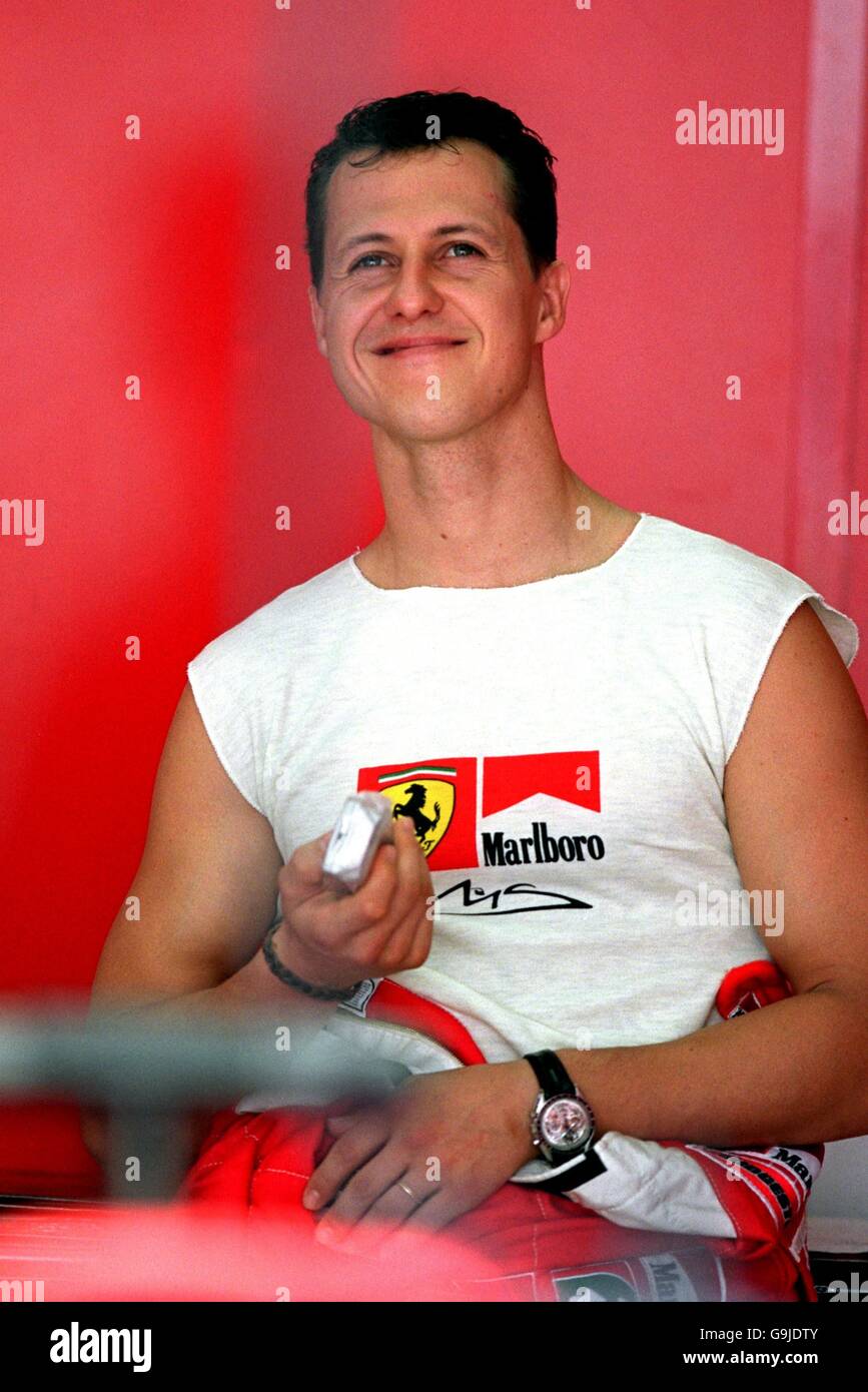 Dressed for the heat Michael Schumacher watches the lap times before taking to the track for practice at the Malaysian Grand Prix Stock Photo Alamy