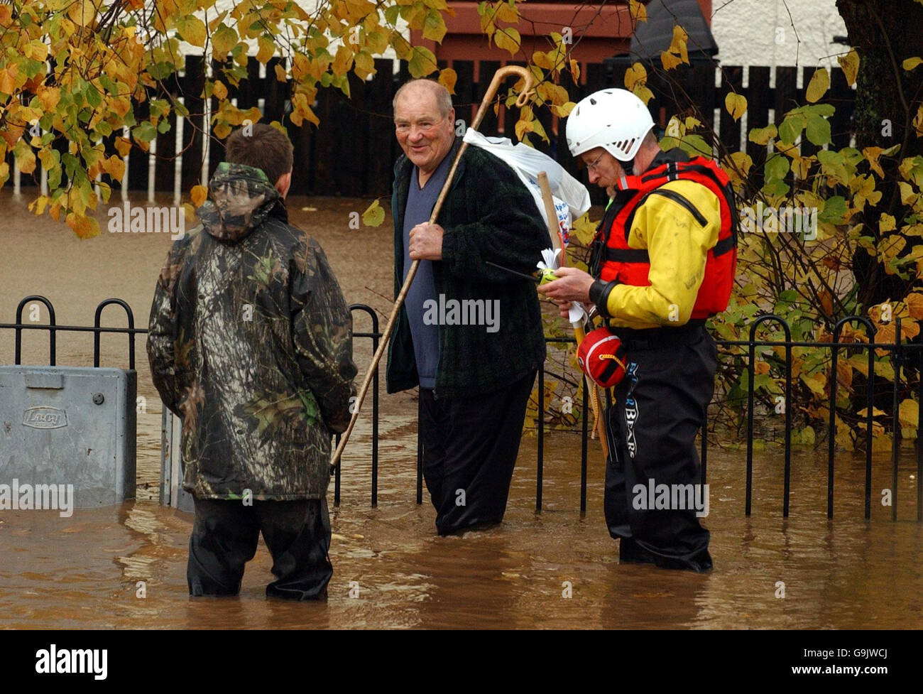 An emergency service worker and locals make their way through floodwaters following flooding in Dingwall near Inverness. Stock Photo