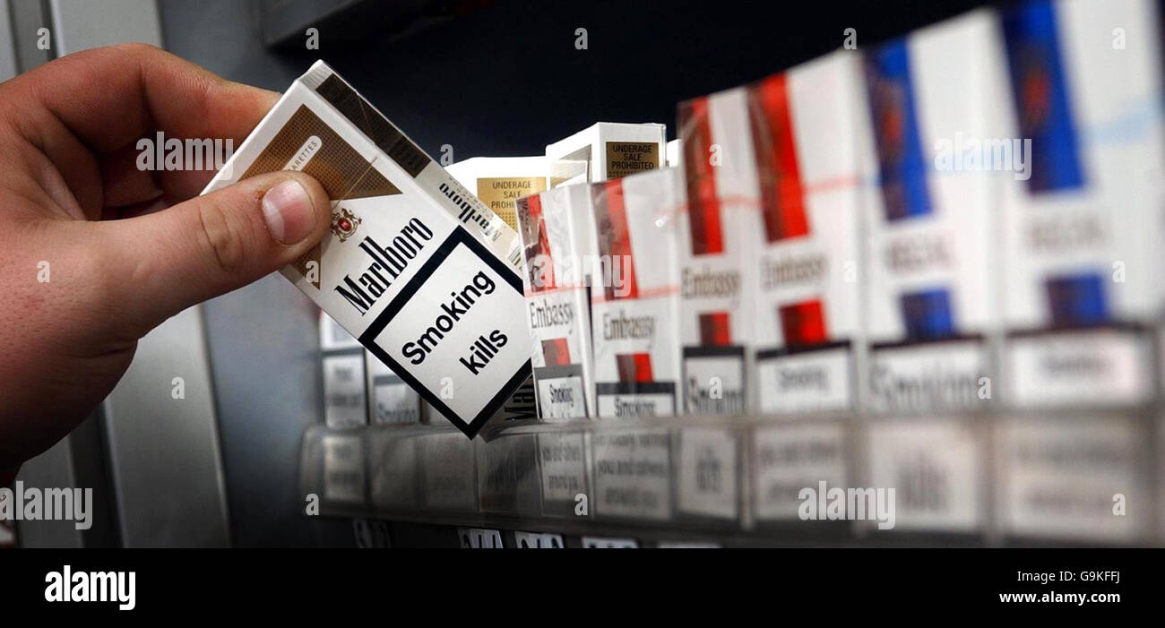 A shop assistant reaches for a packet of cigarettes in a Glasgow shop, after plans to raise the legal age for buying cigarettes to 18 in Scotland were unveiled yesterday. Stock Photo