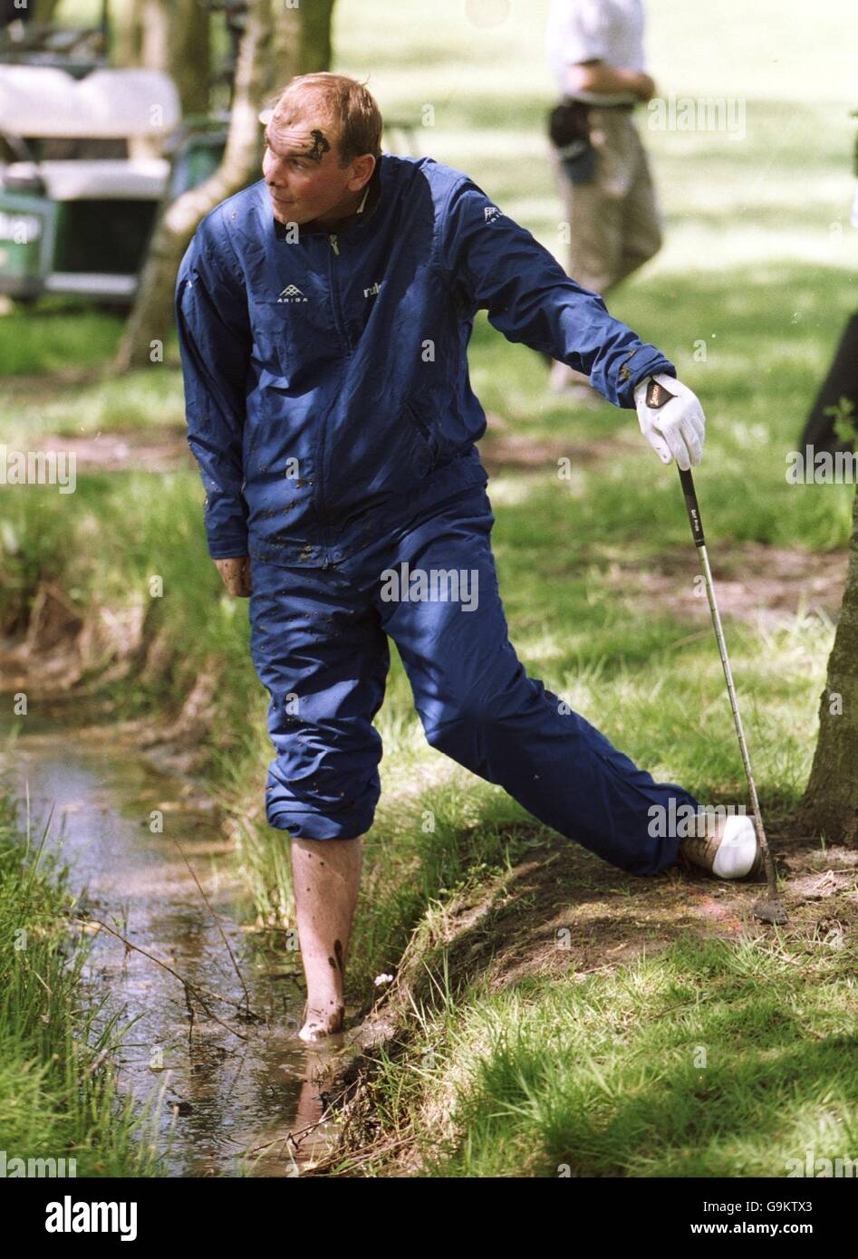 Thomas Bjorn stands covered in mud after playing out of a muddy ditch on the fourth hole Stock Photo