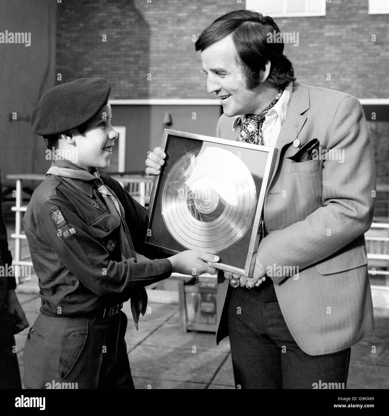 Disc jockey Alan 'Fluff' Freeman (r) presents a gold disc to 13 year-old Paul Newman (l), a boy scout from the 25th Coventry Scout Group who were awarded the disc for selling more copies of the CBS 'Golden Hits' album than any other group in the country. Stock Photo