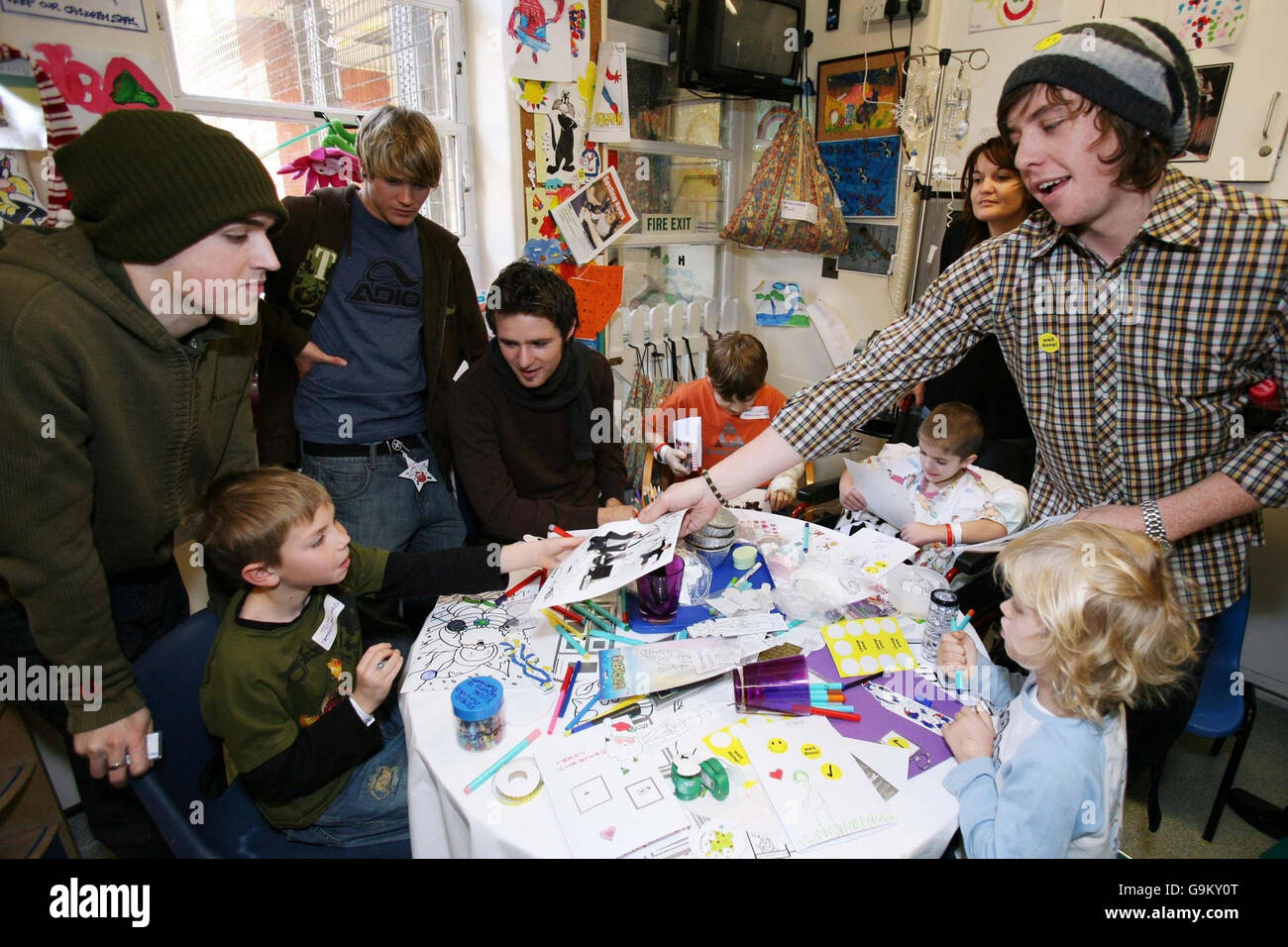 Danny Jones (right), of McFly, hands an autographed band photo to Tom Ursell, age 8 of Epson, as the other members of the band, (left to right) Tom Fletcher, Dougie Poynter and Harry Judd, look on at Great Ormond Street Children's Hospital in central London. Stock Photo