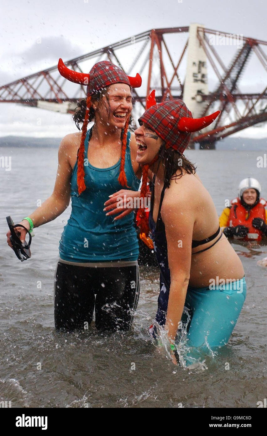 Maxine Smith (left) and Laura Watts throw themselves into the icy waters of the Firth of Forth for the 21st Loony Dook charity swim as Hogmanay celebrations continue in Edinburgh. Stock Photo