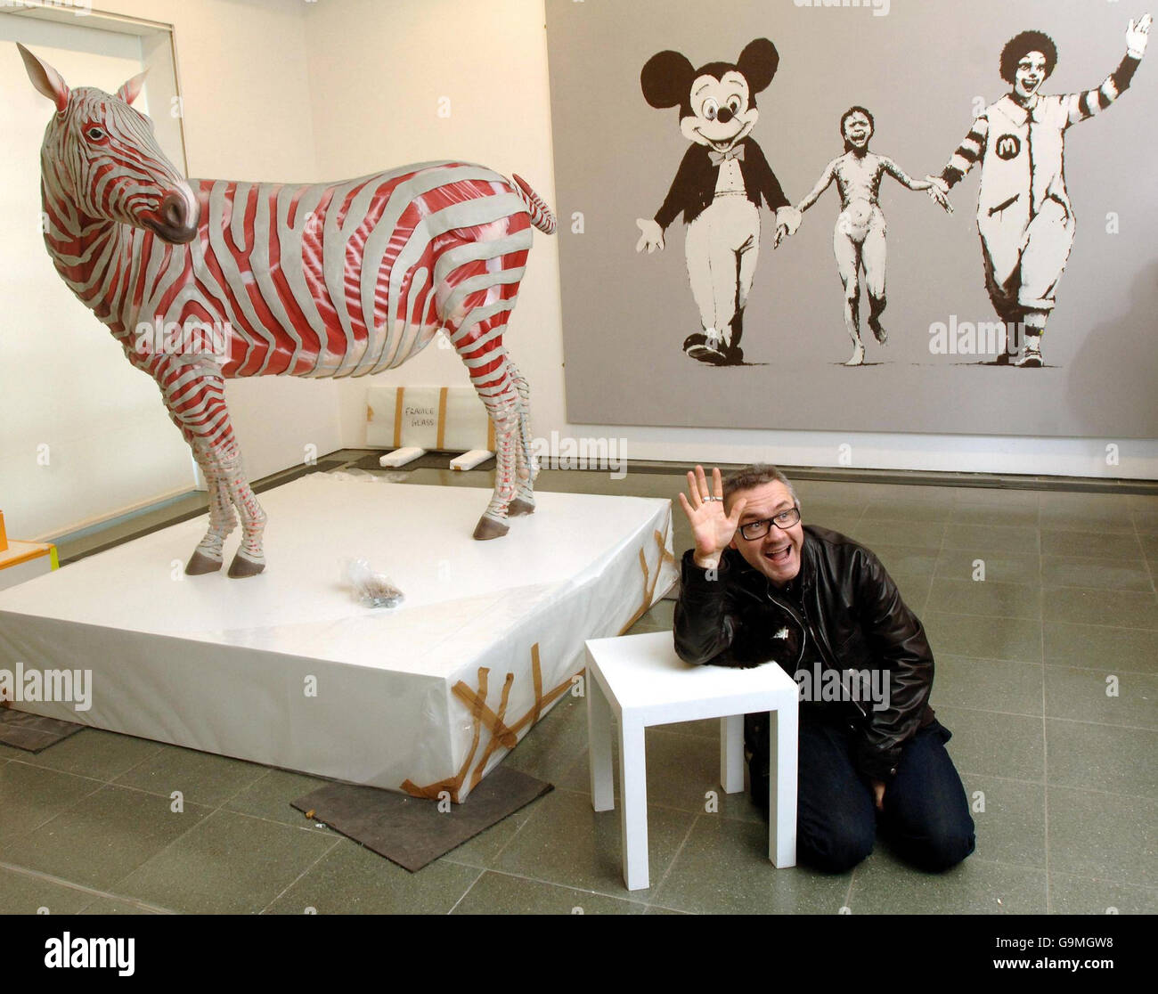 British artist Damien Hirst with some works from 'murderme', his personal contemporary art collection, which he is exhibiting at London's Serpentine Gallery from tomorrow. He is seated with, left, Stripped by Michael Joo and Can't Beat the Feeling by Bansky. Stock Photo