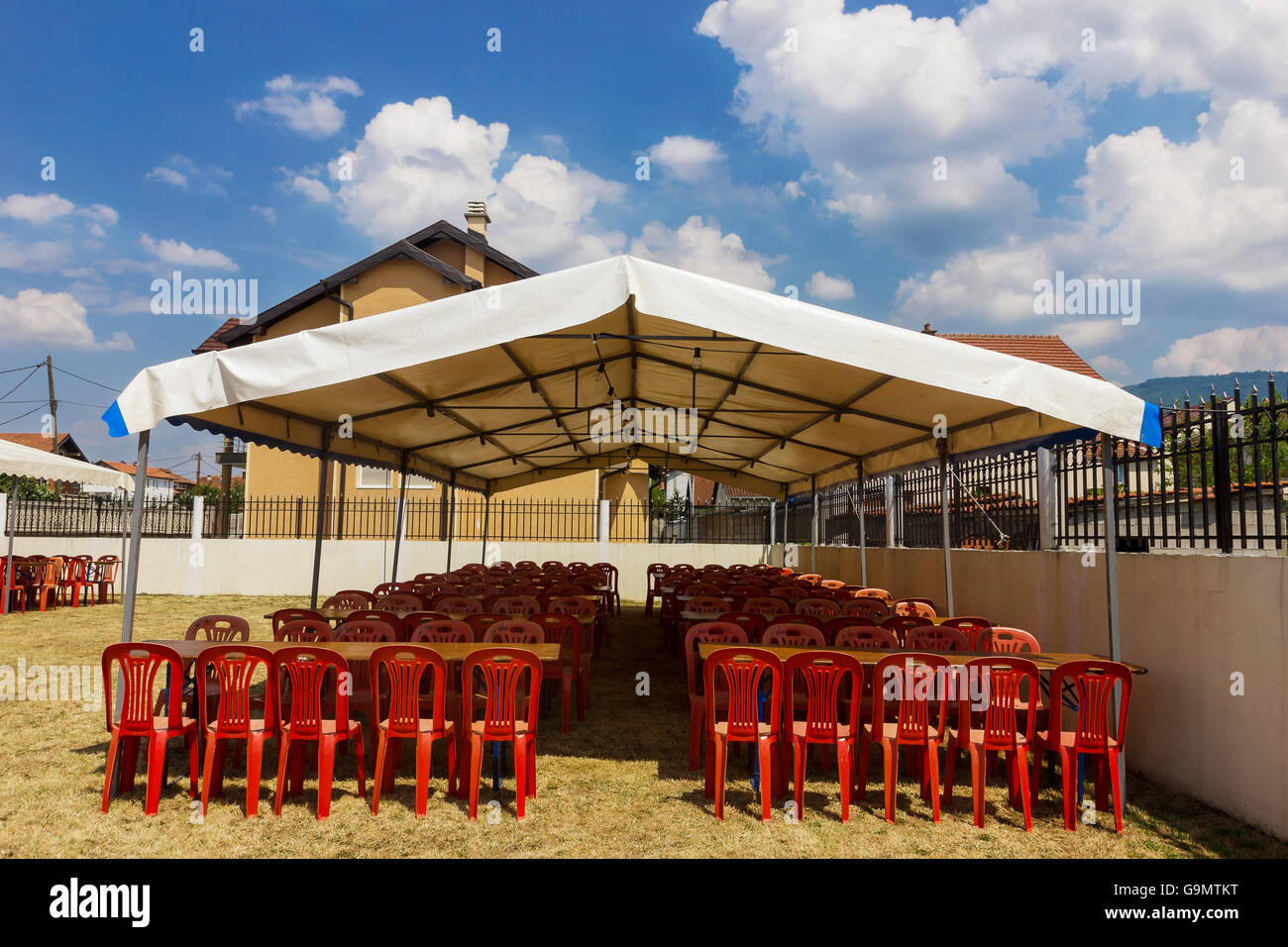 White Entertainment Tent With Red Plastic Chairs In The