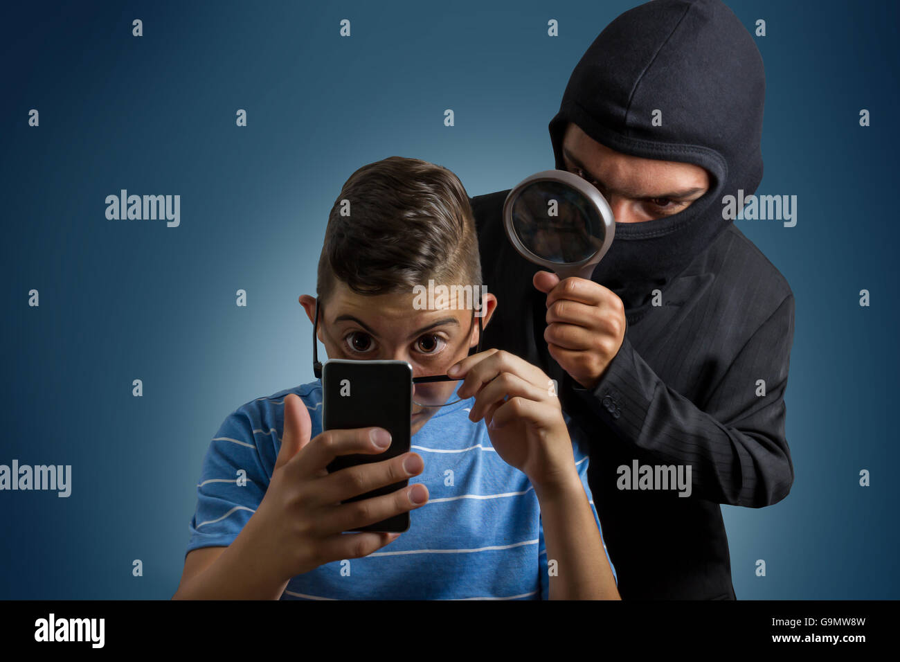 comic masked man spying data from smartphone of teenager Stock Photo