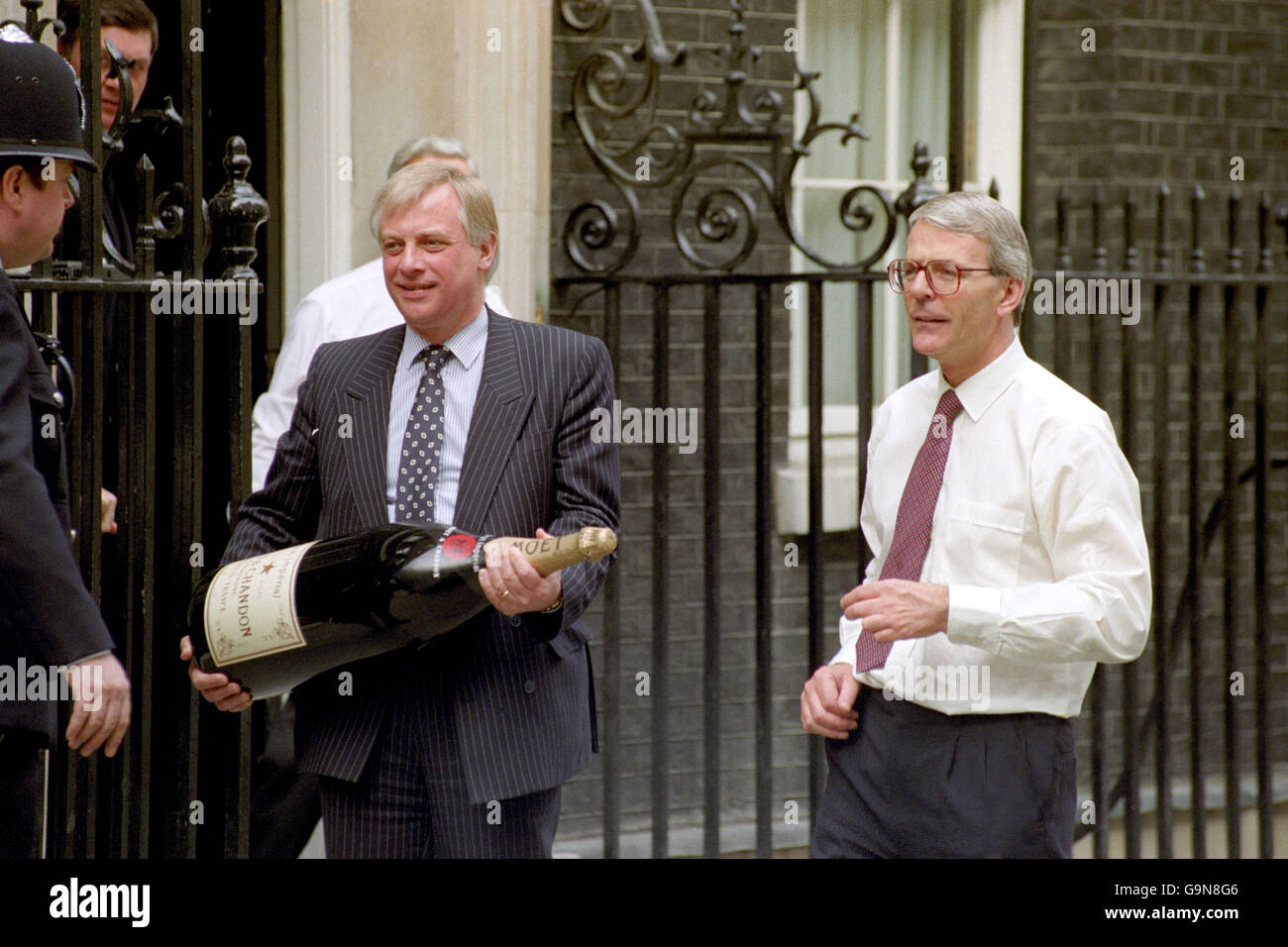 Conservative Party chairman Chris Patten (l) carries a nebuchadnezzar of champagne along Downing Street to celebrate the re-election of Prime Minister John Major (r) Stock Photo