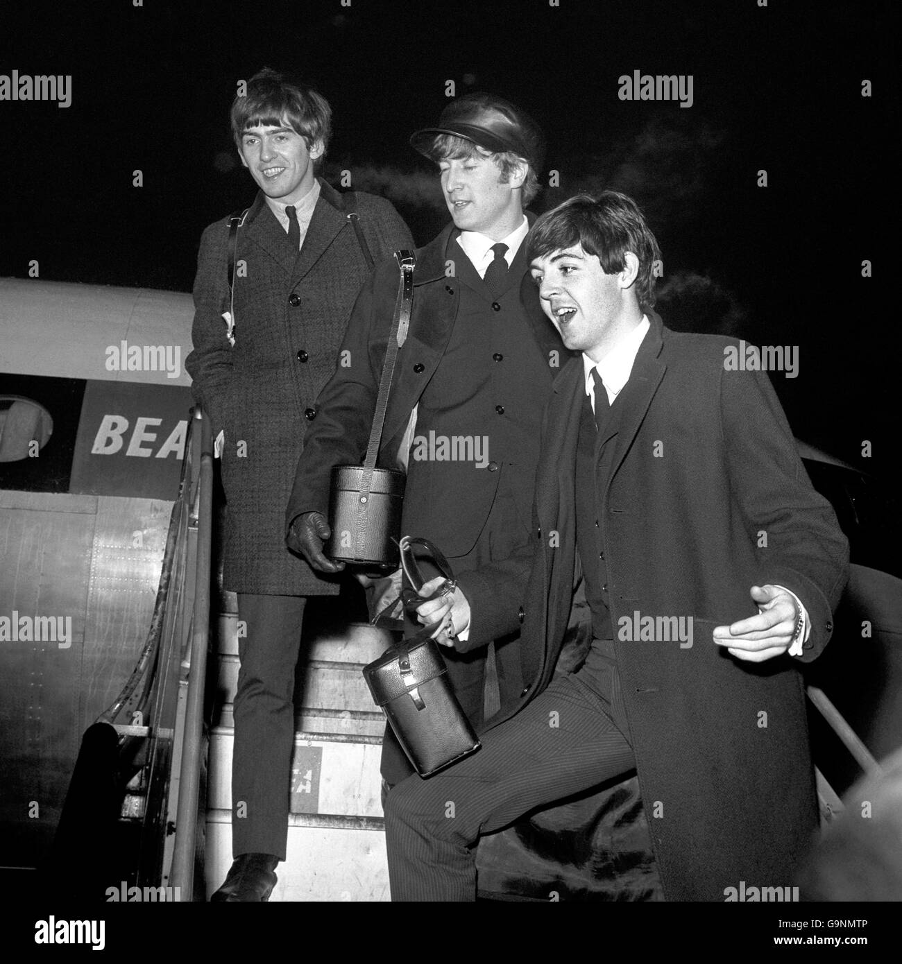 Three of The Beatles pop group board an airliner for Paris at London Airport. Left to right: George Harrison, John Lennon and Paul McCartney. Ringo Starr was left stranded in Liverpool owing to fog. Stock Photo
