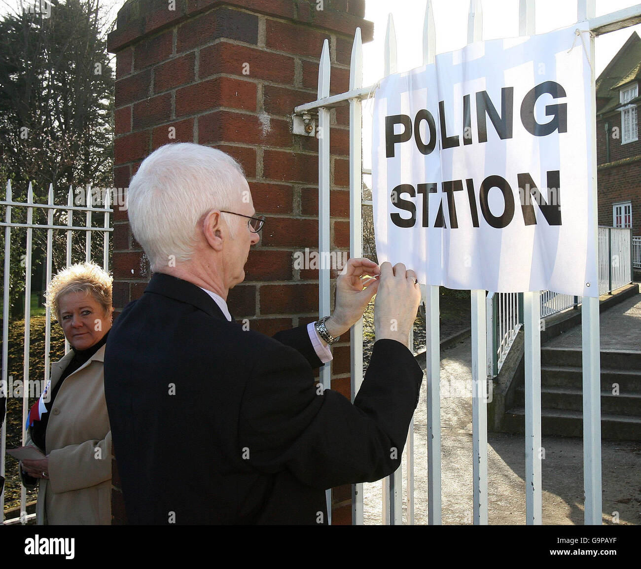 An electoral officer ties a polling station sign to the railing at Elm Grove Primary School in east Belfast. Stock Photo