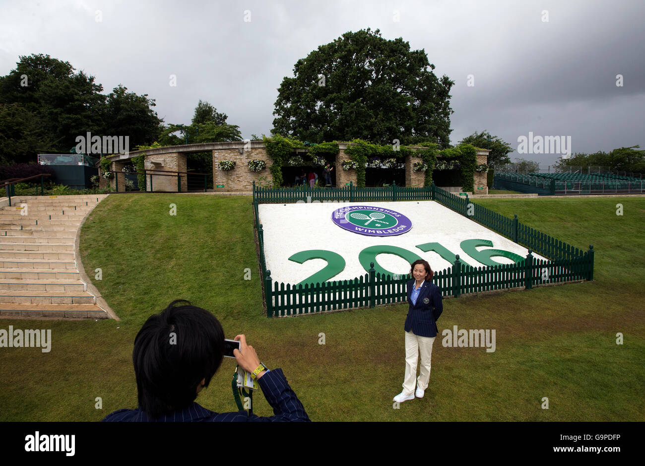 A Wimbledon line judge poses for a photo in front of a Wimbledon