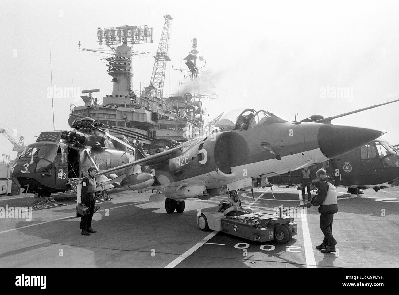 A Harrier jump jet and helicopter on the flight deck of the aircraft carrier HMS Hermes as she headed south for the Falklands. Stock Photo