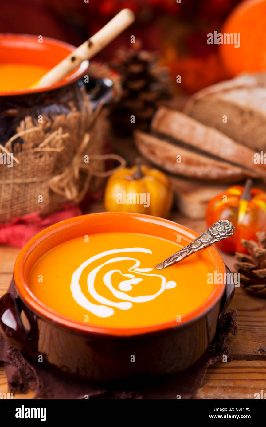 A bowl of homemade creamy pumpkin soup on a rustic table with autumn decorations. Stock Photo