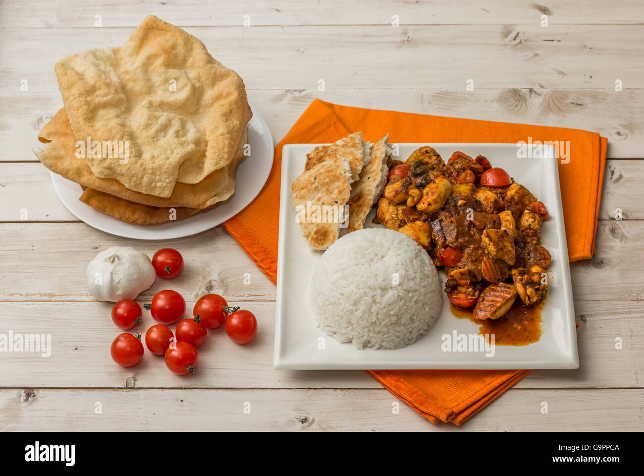 Indian chicken jalfrezi with basmati rice, naan bread and pappadums Stock Photo
