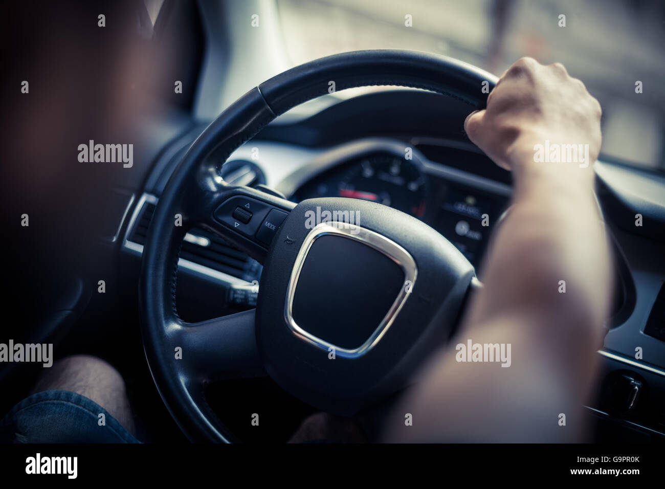 Close up shot of a man's hands holding a car's steering wheel. Stock Photo