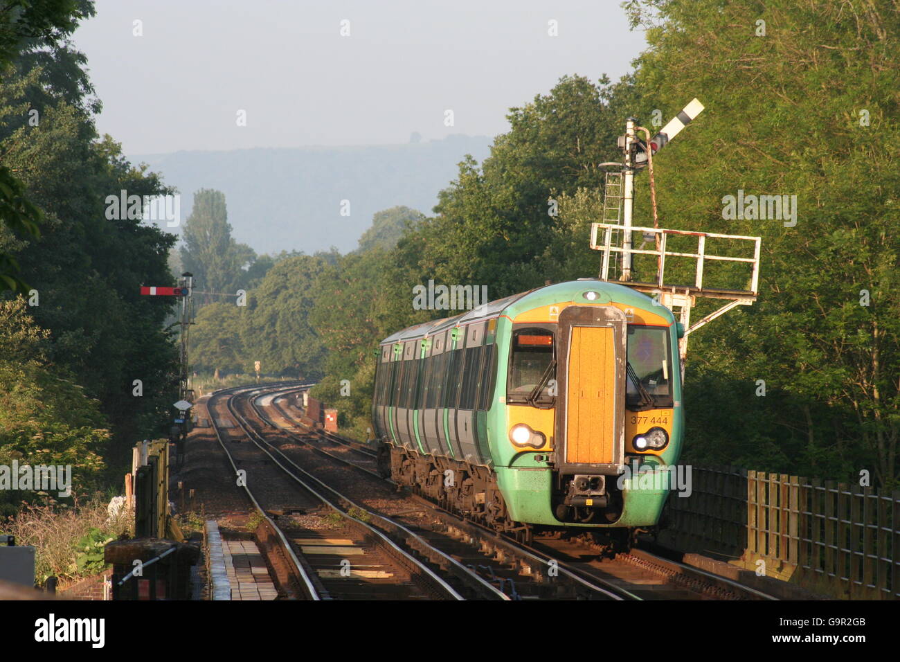 An early Summer's morning sees a commuter train approaching Pulborough Stock Photo
