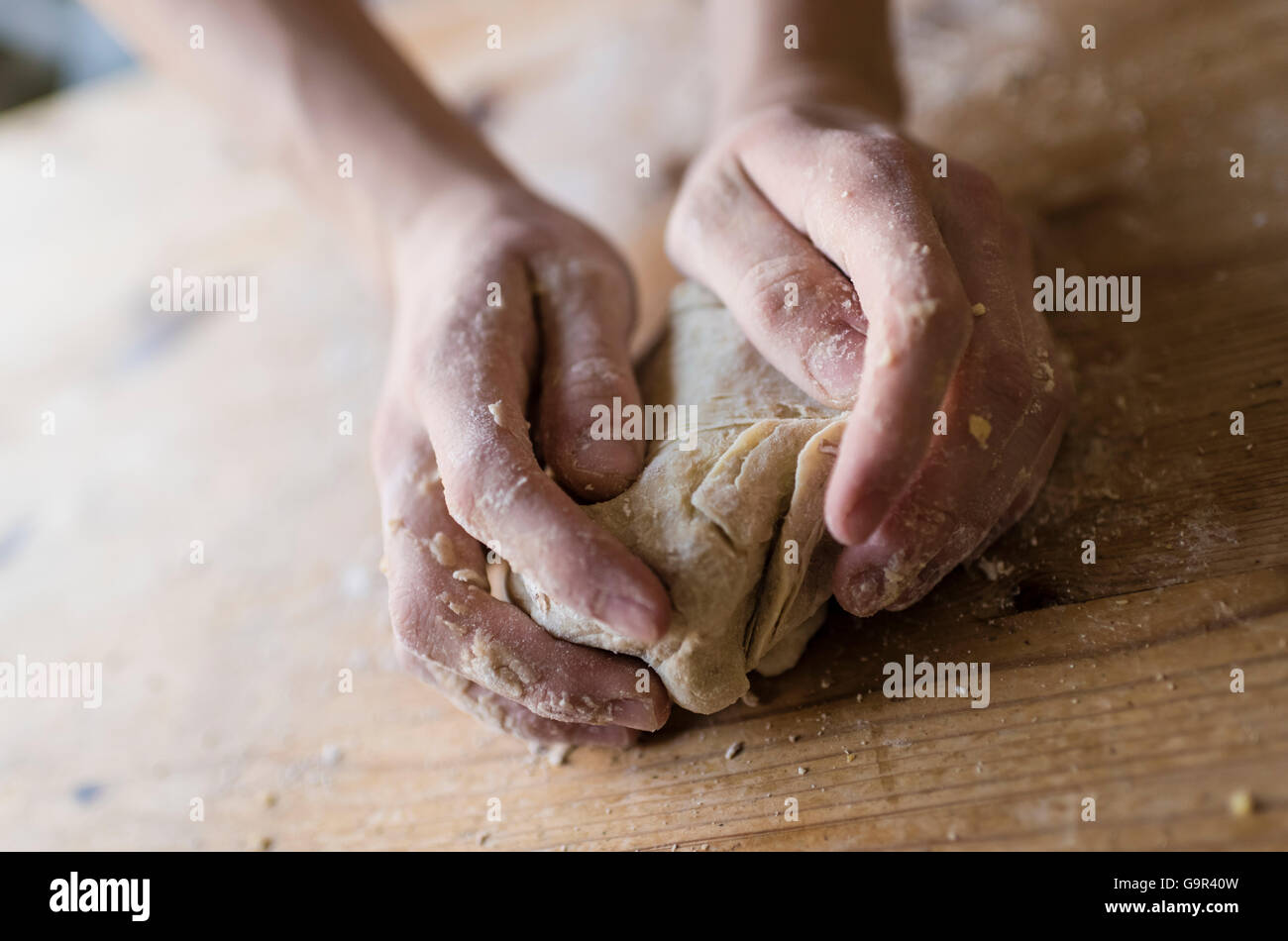 Close-up of two strong hands of a baker that are manually kneading ...