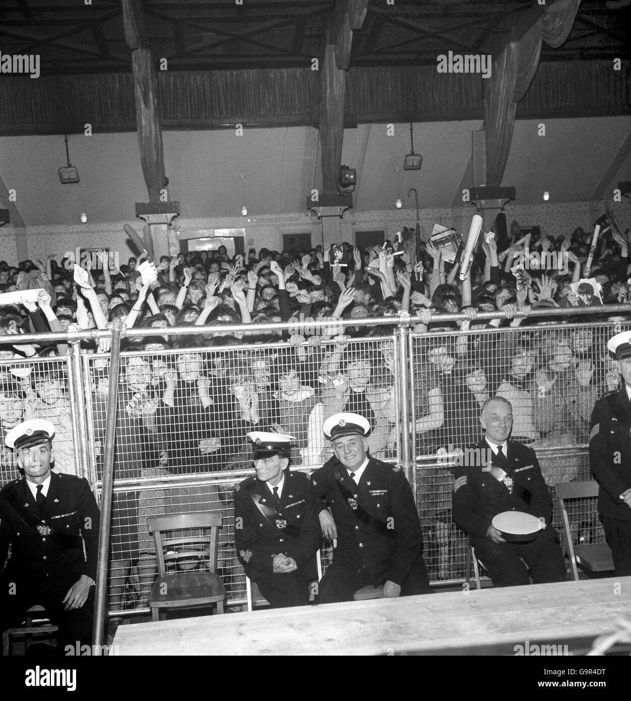 A steel pipe and wire mesh barrier holds back the fans, but not the screams as they yell their support for the Beatles at Wimbledon Palais Stock Photo