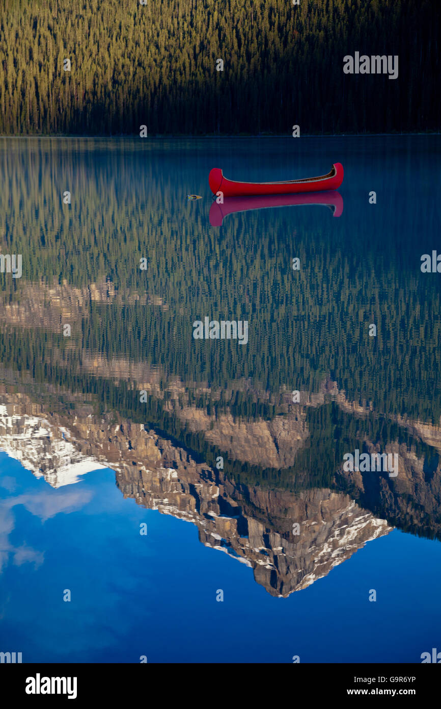 Red canoe anchored on Lake Louise with Rocky Mountains reflection