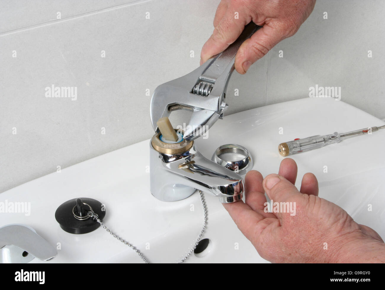 Plumber repairing the faucet of a sink. Stock Photo