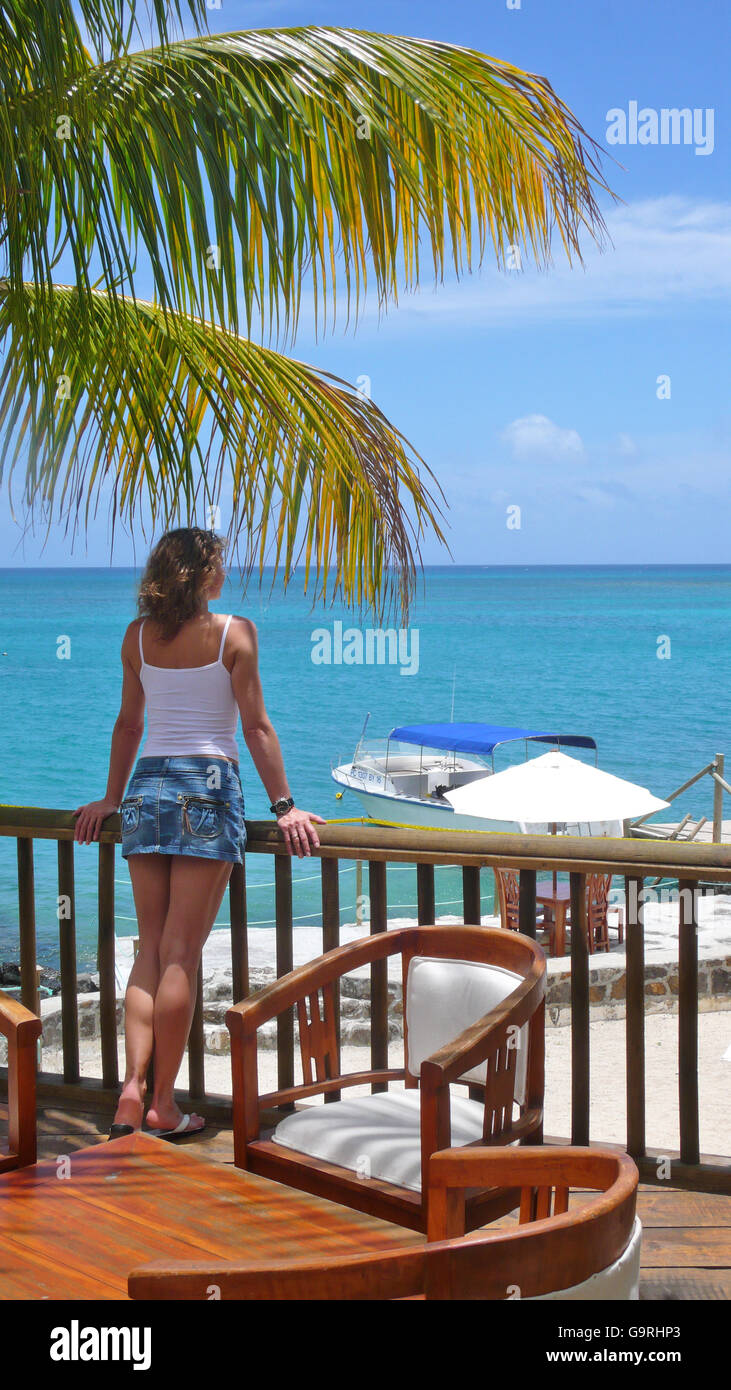 Woman on veranda, looking at the sea, Mauritus Stock Photo