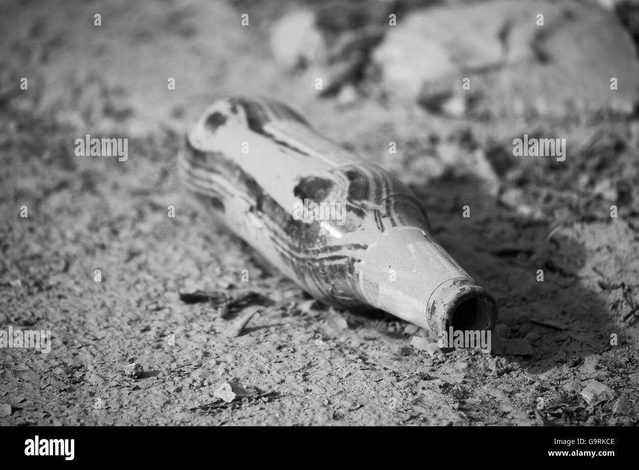 bottle of beer in the mud in black and white Stock Photo