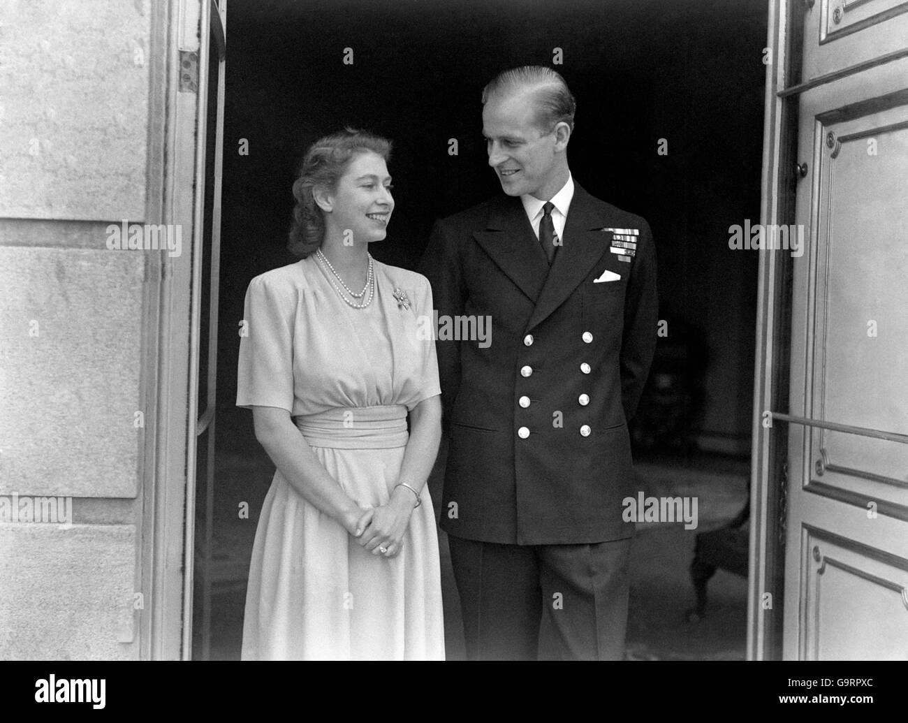 Smiling happily, the Princess and her fiance Lieut. Philip Mountbatten, at Buckingham Palace. Princess Elizabeth's engagement ring is plainly visible Stock Photo