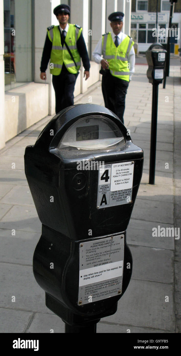 Parking meter stock. Generic stock picture showing a parking meter in central London with traffic wardens in the background. Stock Photo