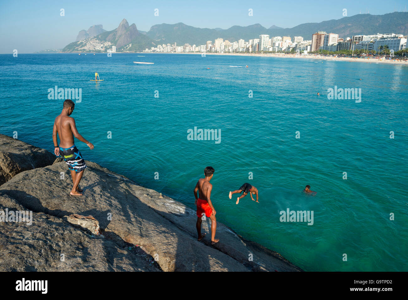 RIO DE JANEIRO - FEBRUARY 03, 2014: Group of young Brazilians gather to jump from the rocks at Arpoador at Ipanema Beach. Stock Photo