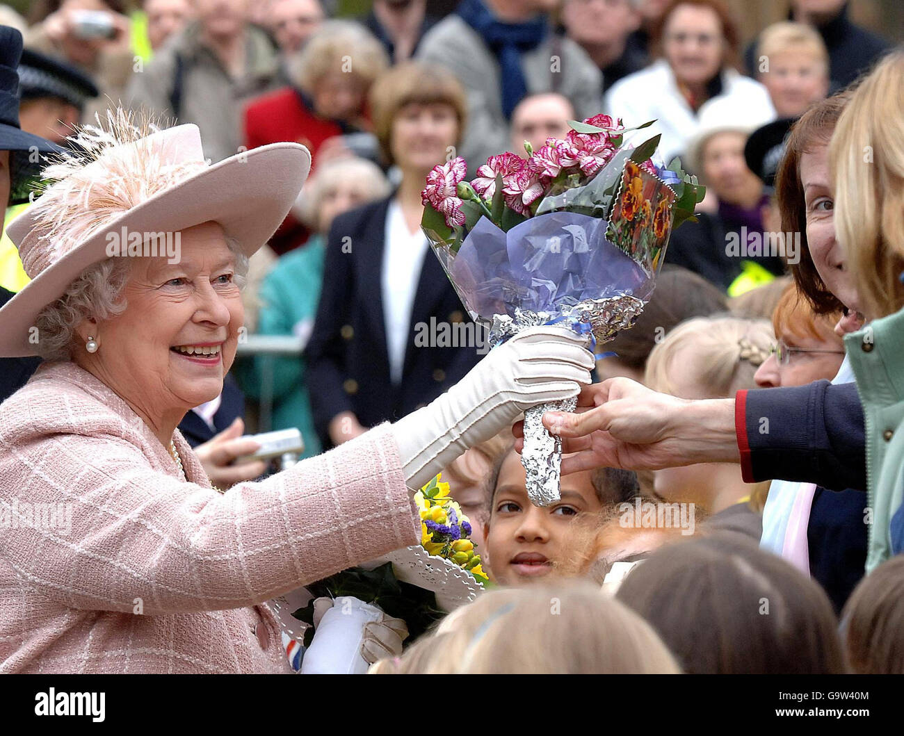 Britain's Queen Elizabeth II is presented with flowers as she begins a walkabout from Manchester Cathedral today following the traditional Royal Maundy Service. Stock Photo