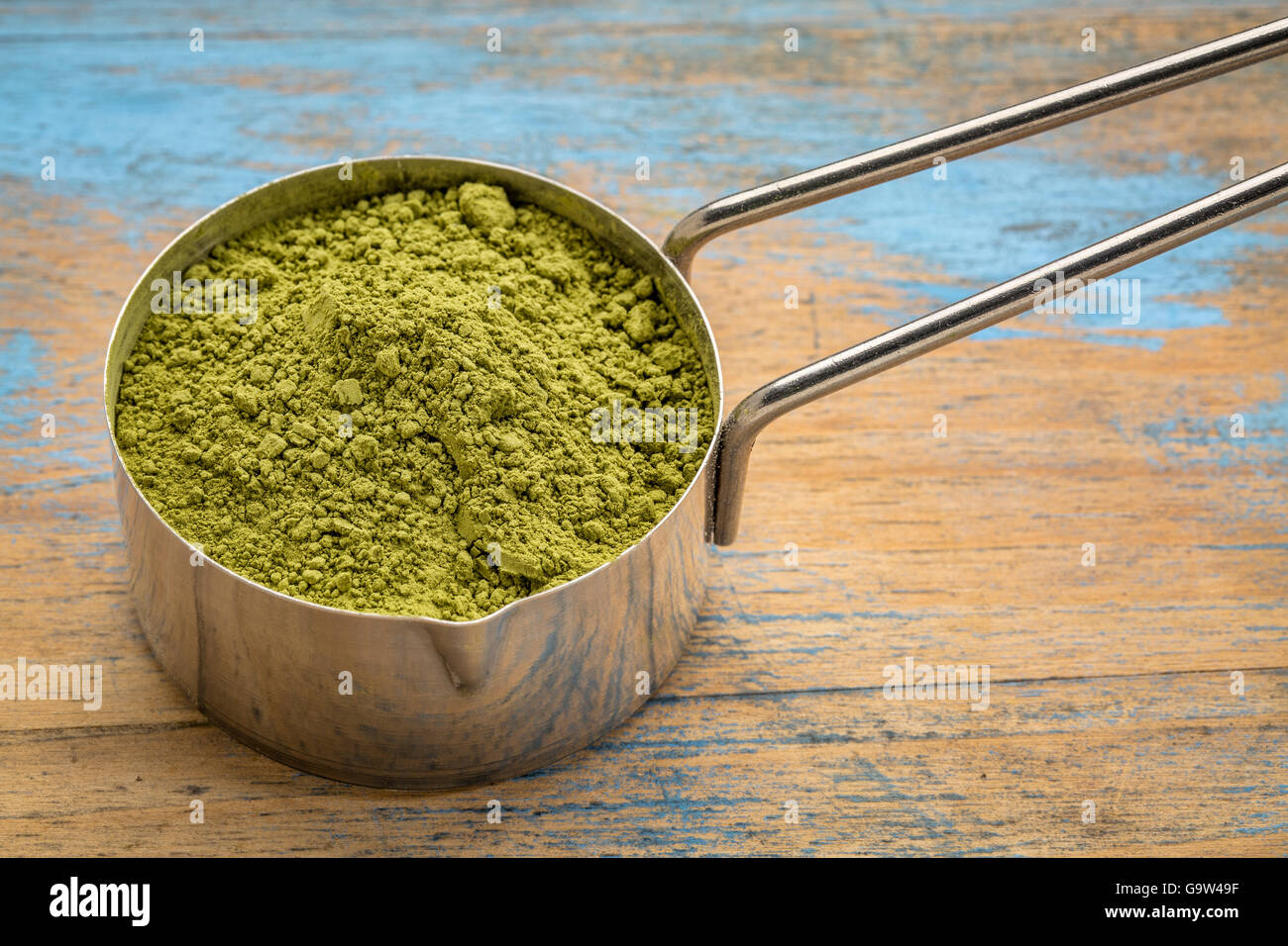 measuring scoop of organic matcha green tea powder against grunge wood Stock Photo