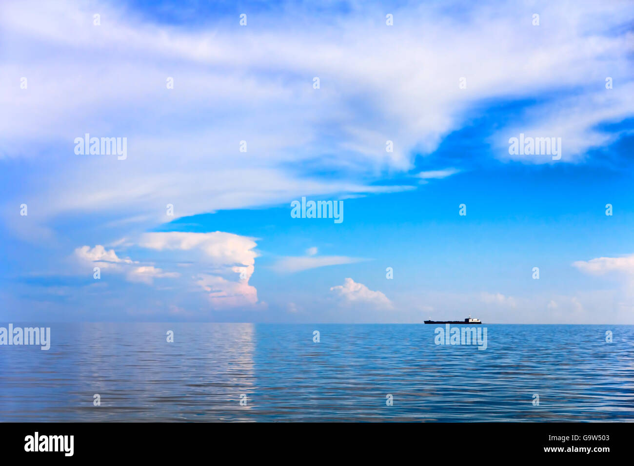 Sea and cloudy sky landscape with alone cargo ship on horizon distance ...