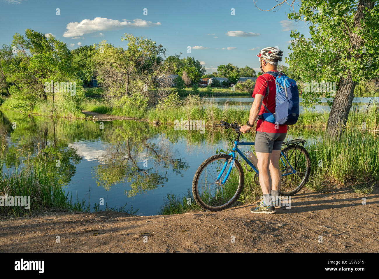 male cyclist with a mountain bike on a lake shore, summer scenery in Colorado Stock Photo