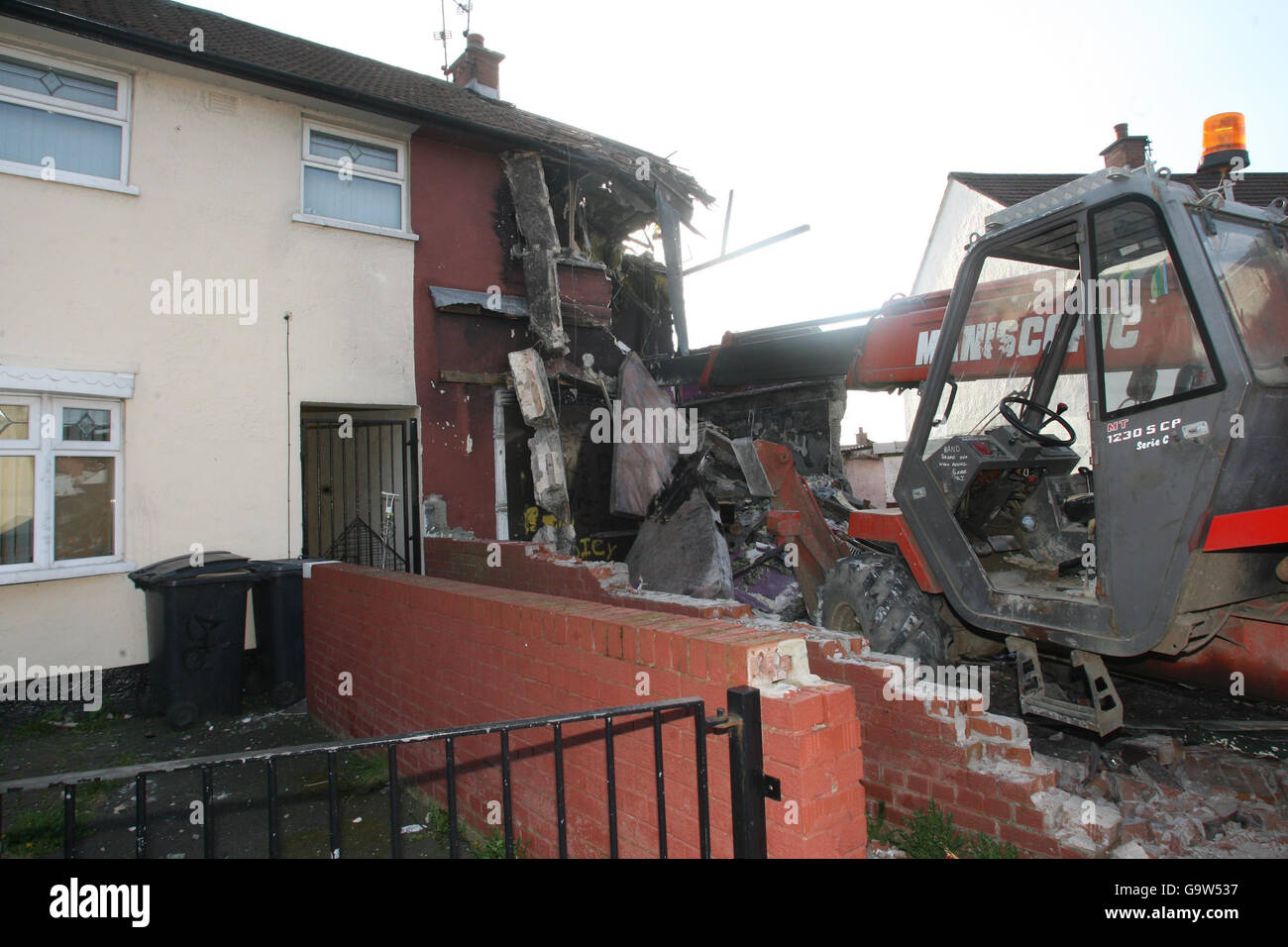 A digger sits in front of the ruined remains of a house in Whitecliffe Parade, Belfast. Stock Photo