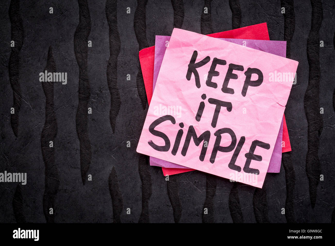 Keep it simple reminder or advice - handwriting on a sticky note against black Nepalese lokta paper Stock Photo
