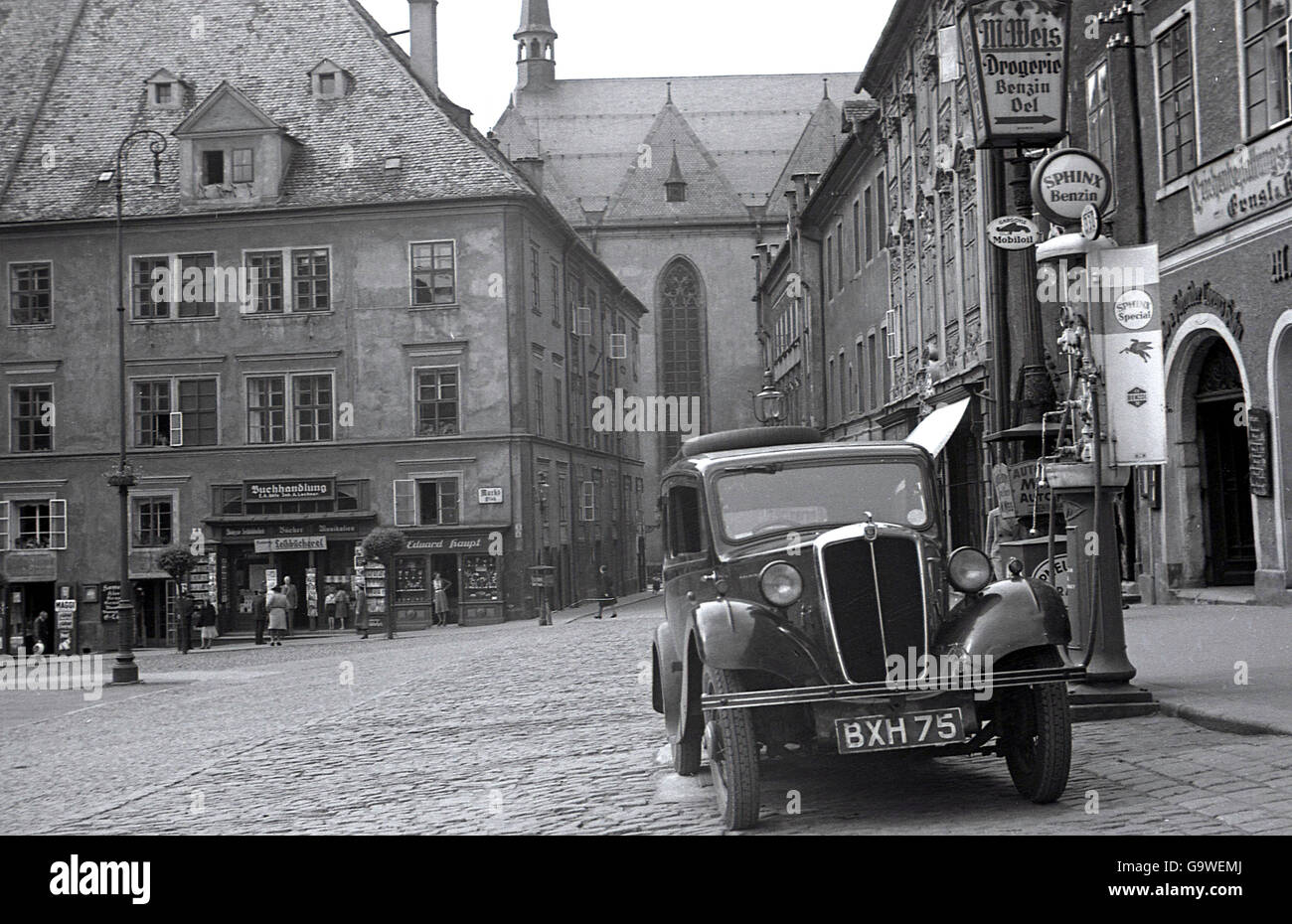 1930s, historical picture of a car with a British numberplate parked at a street petrol pump in thecobbled paved town square of Cheb (Eger) in the Sudetenland, in pre-ww11 Czechoslovakia. Being near the German border irt was part of a German-speaking area referred to as  Egerland. It was annxed in 1938 by Germany. Stock Photo