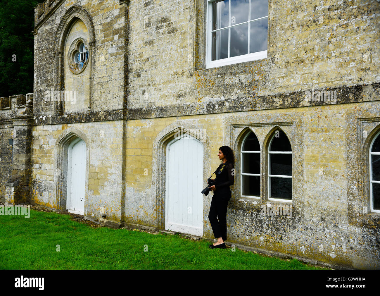 Young lady with a camera leaning on the wall of Fort Henry and admiring beautiful landscapes overlooking lakes behind Gothic style pleasure house. Stock Photo