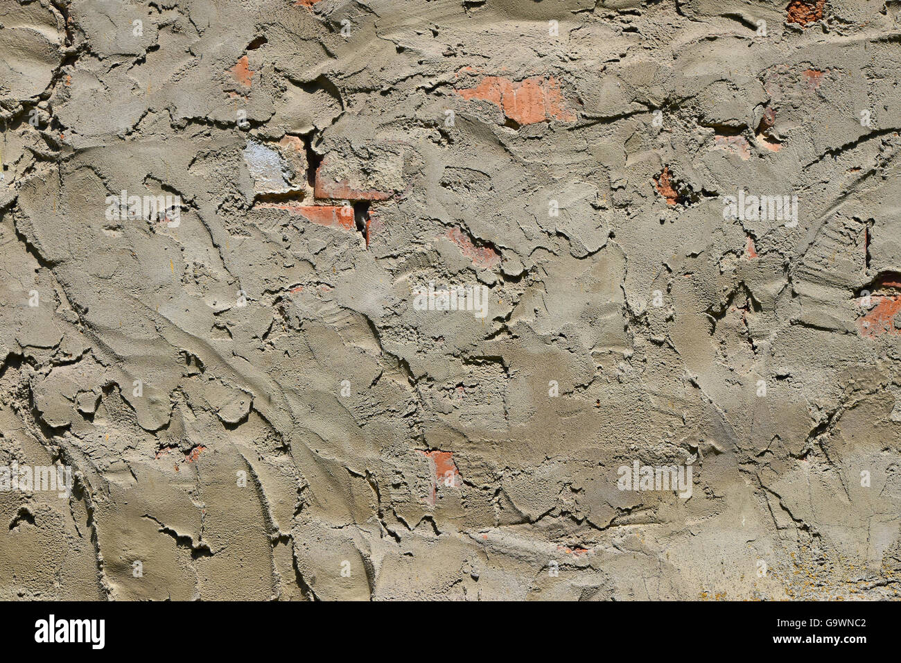 Cement uneven rough plastering layer on unfinished brick wall of construction site Stock Photo